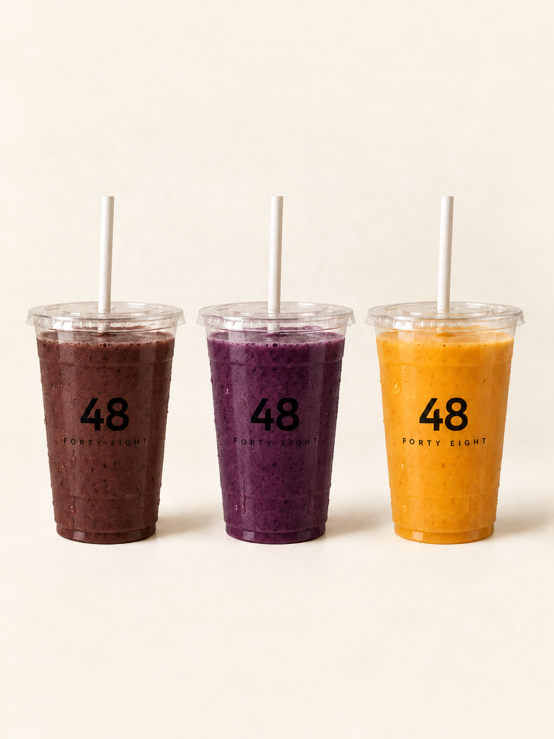 Three Fresh Smoothies in clear plastic cups with flat lids, straws and the Forty Eight logo