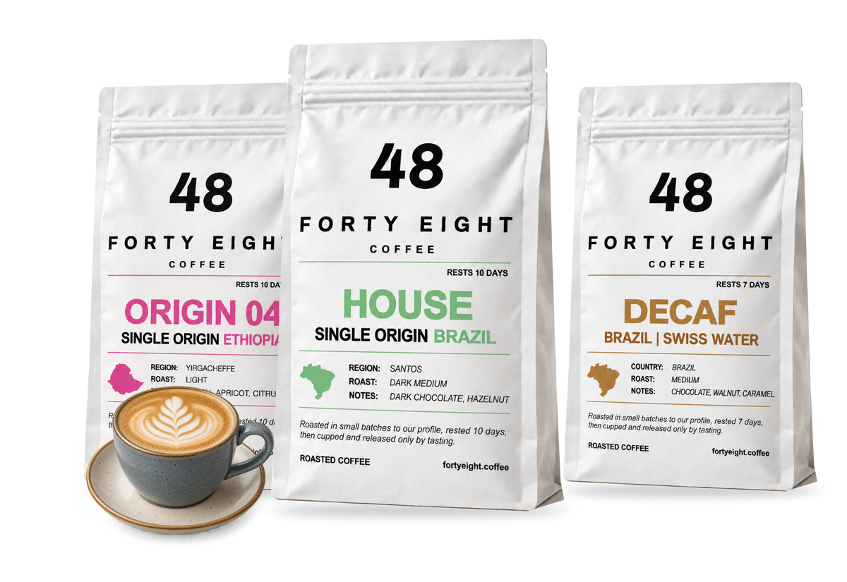 HOUSE, ORIGIN 04 and DECAF white coffee pouches beside a flat white